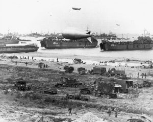 US Navy LSTs deliver vehicles to a beach in Normandy, likely D-Day +1 [Public domain]